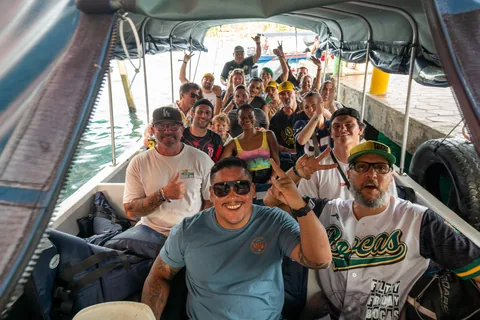 A group of fans in Bocas jerseys smiling on the boat to the game